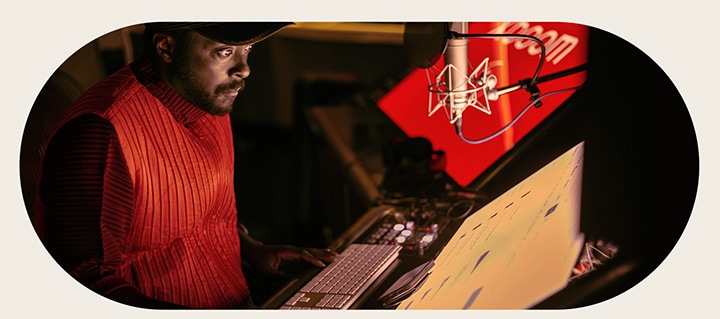 will.i.am ?ang làm vi?c trong phòng thu, nhìn vào màn hình ??t phía d??i micro.