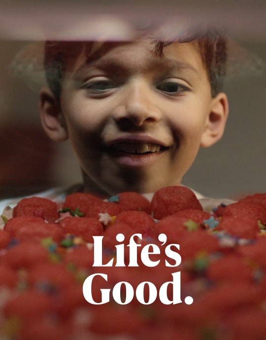 Un enfant souriant admirant les fraises sur le dessus d'un gateau, l'air heureux et excité.