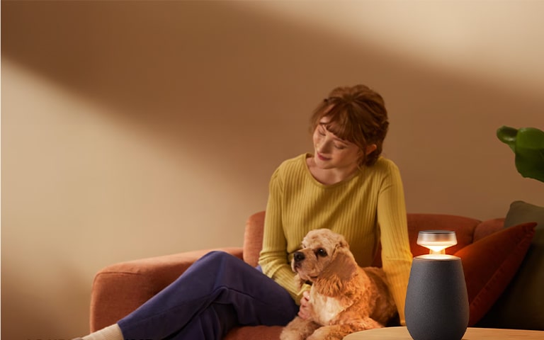 Frau und Hund genie?en den Klang der tragbaren, drahtlosen Bluetooth-Lautsprecher LG XBOOM 360 mit Surround-Sound-System