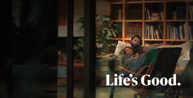 A man and a woman are lying on a sofa, looking relaxed and happy. At the bottom of the image, “Life’s Good.” is written in white.