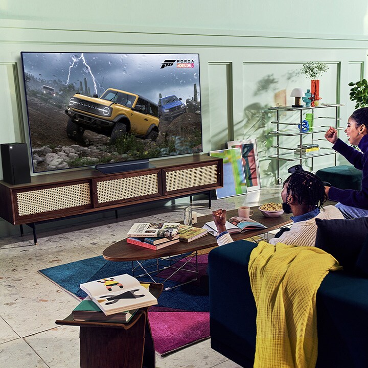 A person plays a racing game with an XBOX Series X|S controller on an LG OLED television