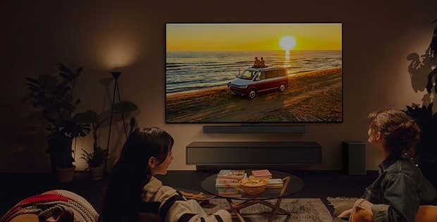 Mysigt rum med LG TV p? v?ggen och tv? personer som sitter i soffan