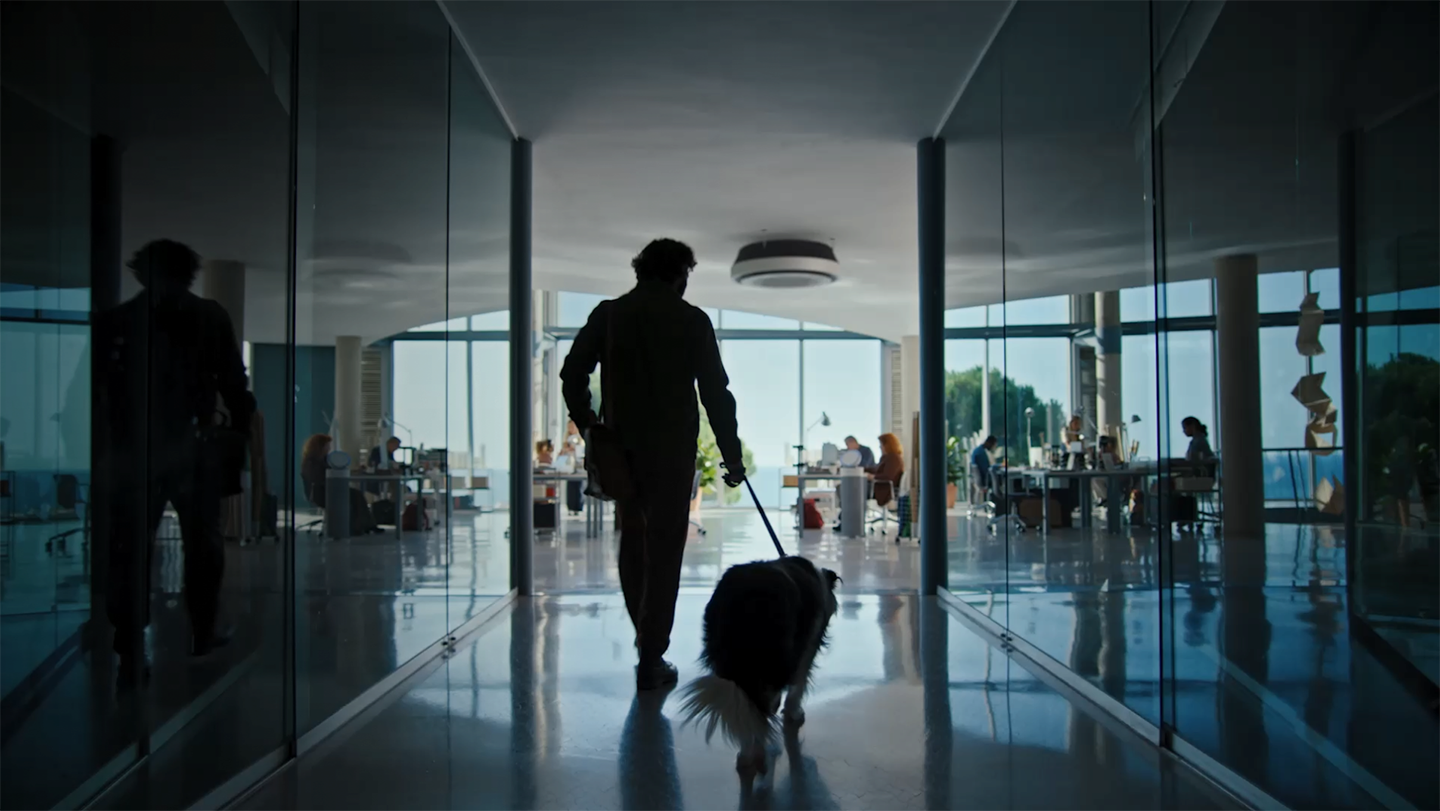A man holding a dog leash heads to an office. Another man wrinkles his nose and touches it, seemingly reacting to a bad smell. Behind the dog, the LG Puricare air purifier comes into view. The man gestures in dissatisfaction, and a red light turns on in the air purifier.