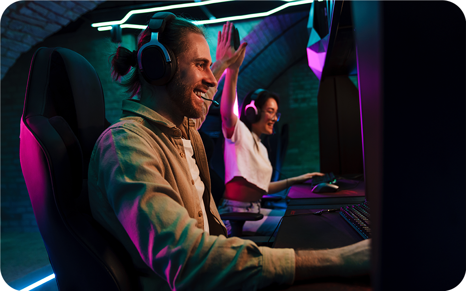 Dva hrá?i se intenzivně soust?edili na 4K monitor ve spo?e osvětlené místnosti a u?ívali si pohlcující zá?itek z videohry.