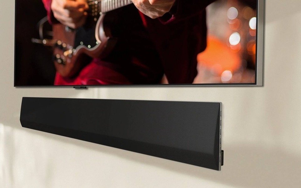 Was macht eine Soundbar, außer verbesserte Klangqualität zu erzeugen? Mit dem richtigen Design wirkt sie wie hier an einer Wand visuell ansprechend und ergänzt den Fernseher für ein hochwertiges Entertainment Setup.
