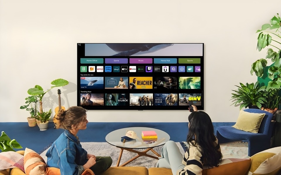 Zwei Personen sitzen in einem gemütlichen Wohnzimmer und nutzen einen Smart-TV ohne Internet, umgeben von stilvollen Möbeln und Pflanzen.