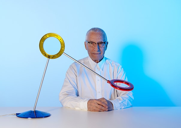 Alessandro Mendini blickt geradeaus und ist mit seiner künstlerischen Skulptur abgebildet.