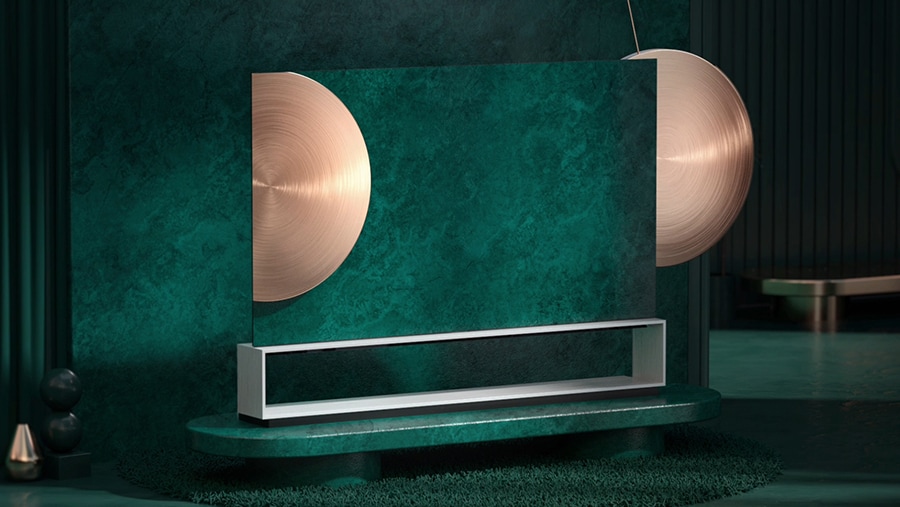 Der Fernseher LG SIGNATURE OLED 8K steht in einem grünen künstlerischen Wohnzimmer mit einem gro?en goldenen Metallpendel.