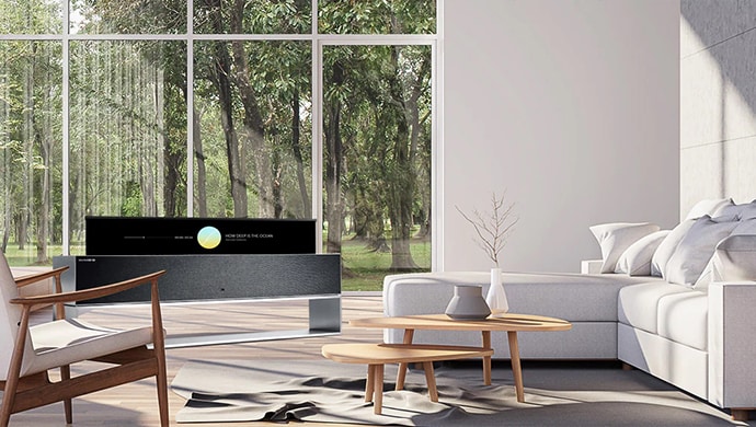LG SIGNATURE R in einem wei?en Themenzimmer vor einem gro?en Fenster mit Waldblick