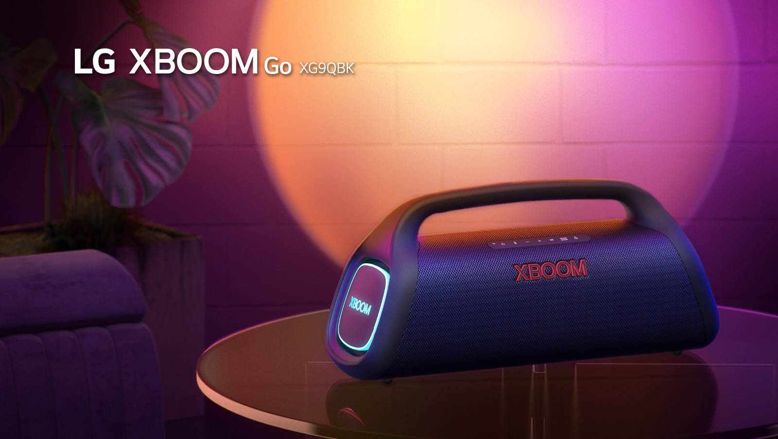 LG XBOOM Go XG9 is placed on the metal table with orange lighting is on. Behind the table, stage lighting is spotlighting the wall.