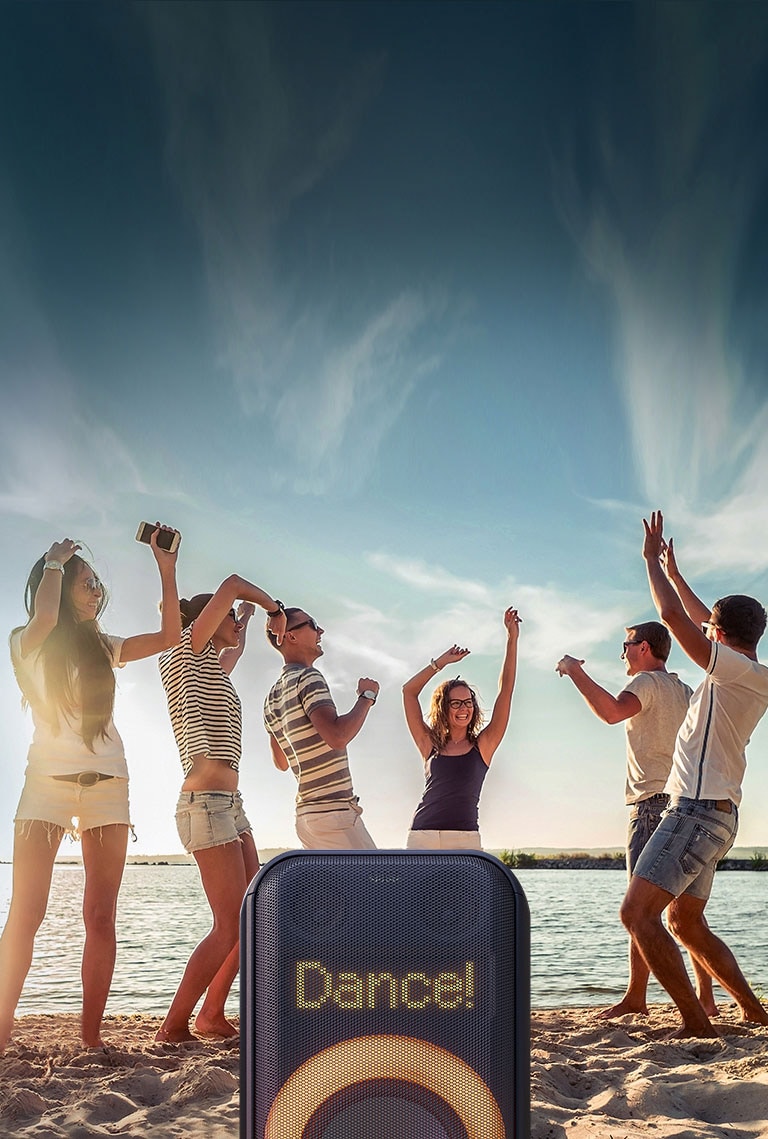 Primer plano de la iluminación de píxeles dinámica. ?Muestra el baile! Texto. Abajo, la iluminación anular multicolor naranja está encendida. Detrás del parlante, la gente está bailando en la playa.
