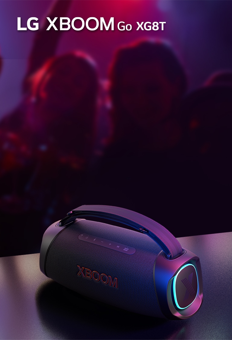LG XBOOM Go XG8T on paigutatud metallist lauale, kus p?leb oran? tuli. Laua taga naudivad inimesed muusikat.