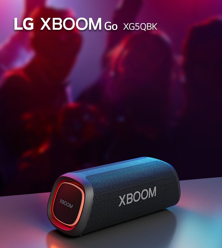 LG XBOOM Go XG5 on paigutatud metallist lauale, kus p?leb oran? tuli. Laua taga naudivad inimesed muusikat.