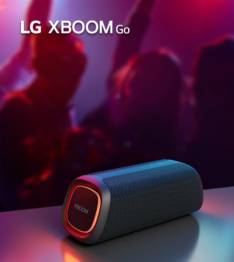 LG XBOOM Go XG7 on paigutatud metallist lauale ja p?leb oran? valgustus. Laua taga naudivad inimesed muusikat.
