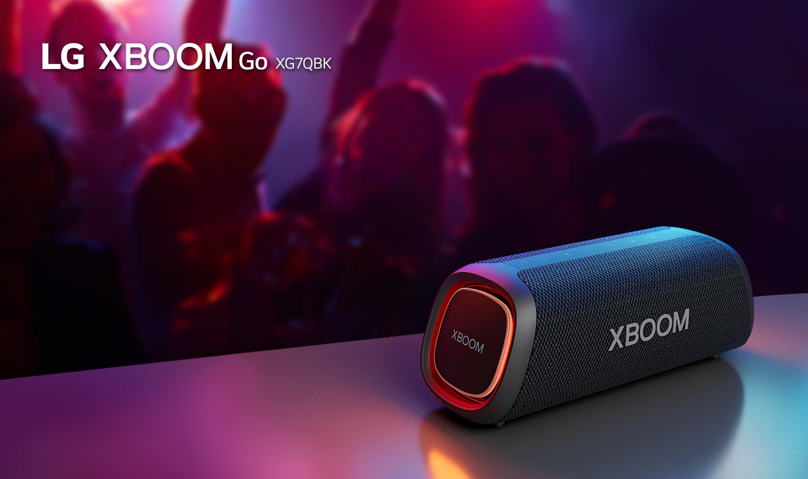 LG XBOOM Go XG7 on paigutatud metallist lauale ja p?leb oran? valgustus. Laua taga naudivad inimesed muusikat.
