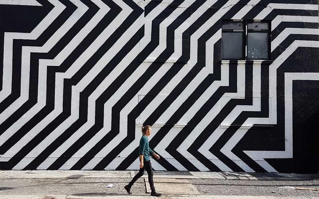 Viaje a Berlín: un hombre pasa frente a un grafiti en blanco y negro en las calles de Berlín