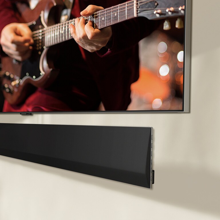 Vinossa kuvakulmassa alareunasta otettu kuva LG TV -televisiosta ja LG Soundbar -??nipalkista, jotka on kiinnitetty sein??n.