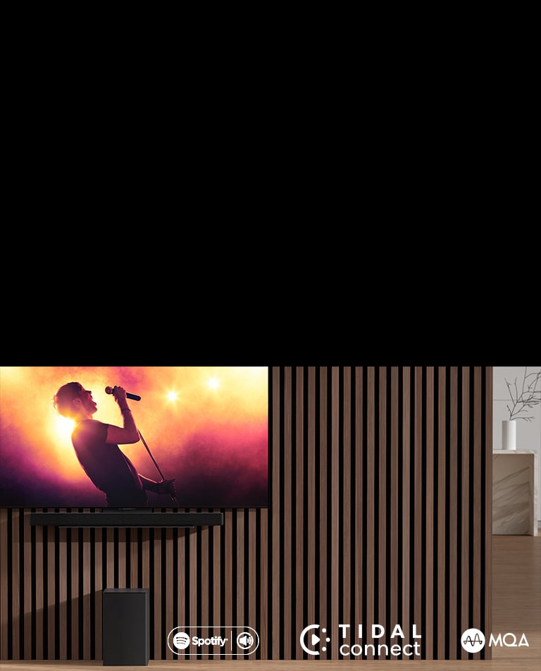 LG OLED C on sein?ll?, ja sen alla LG Sound Bar SC9S on ainutlaatuisessa kiinnikkeess?. Alapuolella on subwoofer. Televisiossa n?kyy konserttin?kym?.