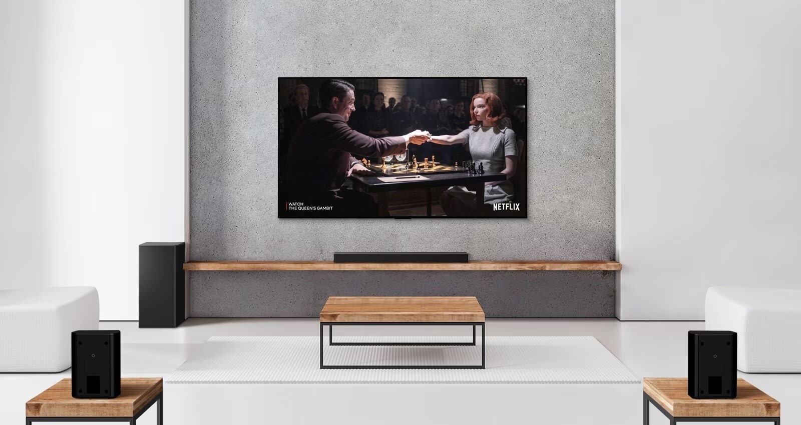 Un salon minimaliste équipé d’une barre de son LG et d’un caisson de basses sous un téléviseur mural. L’écran affiche une série Netflix, et deux haut-parleurs arrière sont positionnés de manière à offrir un son immersif.