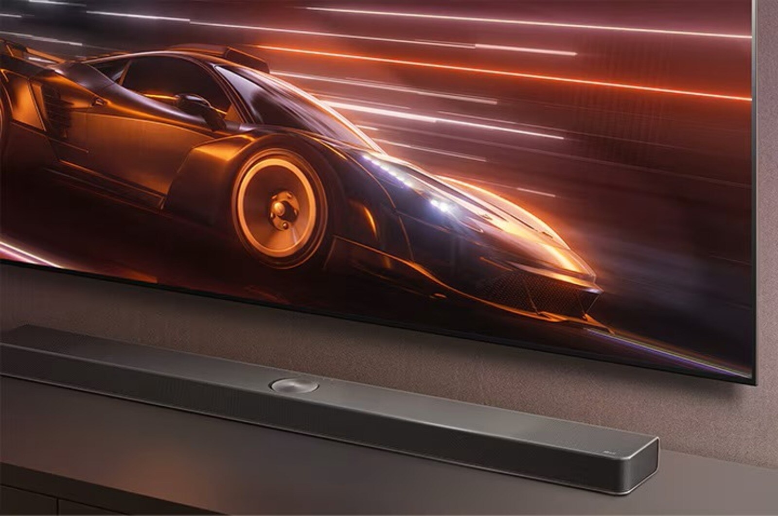 Gros plan sur une barre de son LG placée sur un meuble TV, alors qu’un jeu de course animé s’affiche sur le téléviseur au-dessus, mettant l’accent sur l’expérience de jeu immersive.