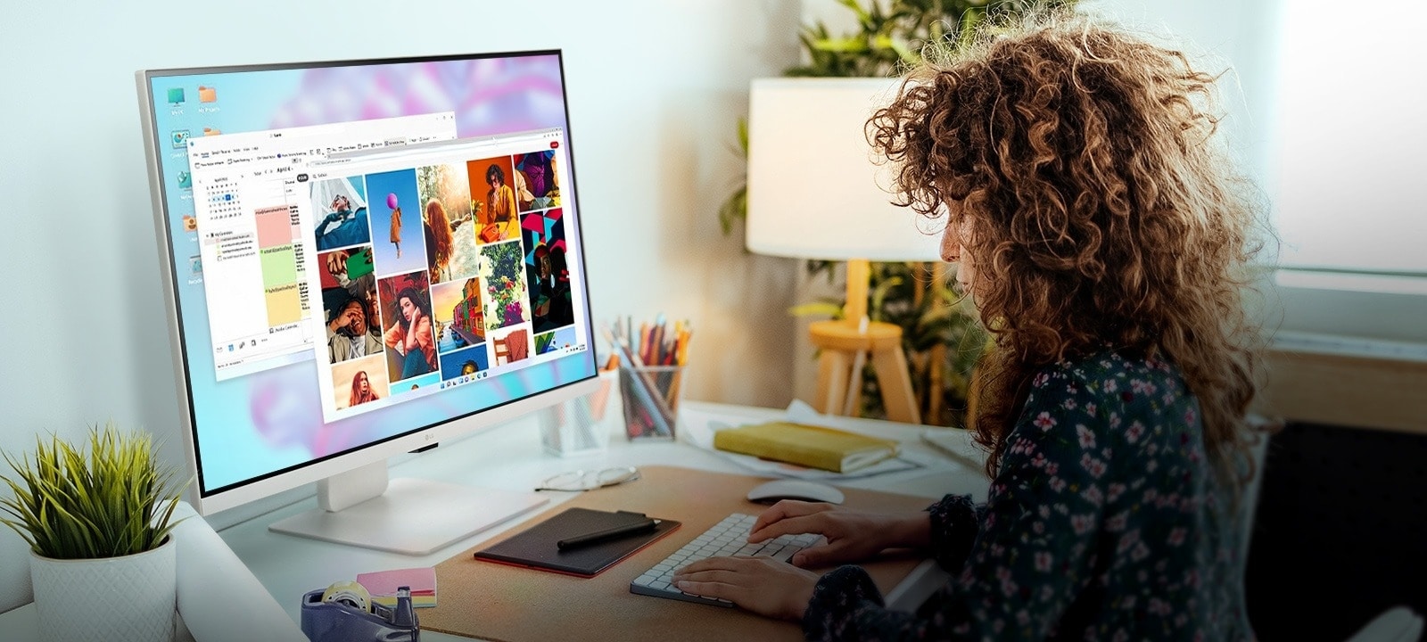 personne travaillant sur un Smart Monitor LG sur lequel s’affichent des images et des documents. Sur le bureau figurent une plante, une lampe et des carnets de notes, le tout dans un bureau à domicile confortable.