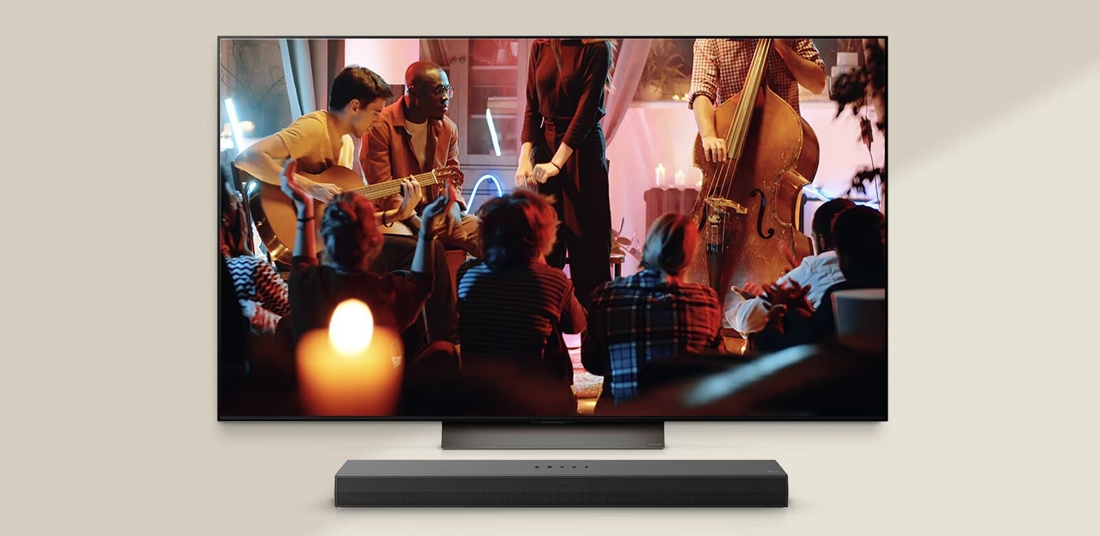 Une TV LG présentant un spectacle de musique en direct avec des musiciens jouant de la guitare et de la contrebasse dans un cadre à l’éclairage chaleureux. Une barre de son LG est placée sous la TV LG, renforçant l’atmosphère immersive.