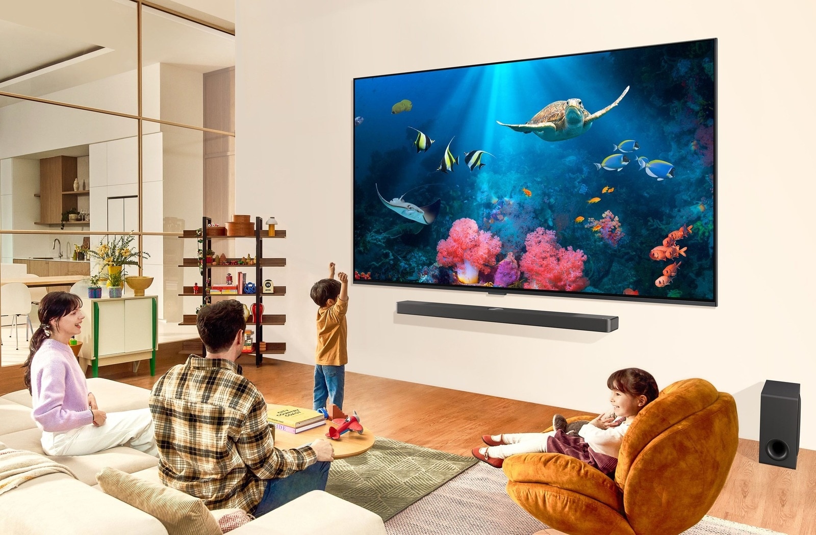 Une famille dans un salon regardant une scène sous-marine avec des coraux et des créatures marines aux couleurs éclatantes sur une grande télévision murale LG. Sous la TV LG, une barre de son LG élégante et un caisson de basses améliorent l’expérience visuelle dans le salon spacieux et moderne.