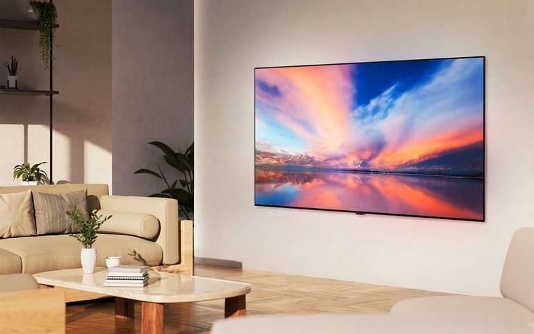 Un salon moderne avec une grande TV murale affichant un coucher de soleil vibrant sur un lac calme, des meubles beiges et confortables, une table basse en marbre avec une plante, et une lumière naturelle douce remplissant l'espace.