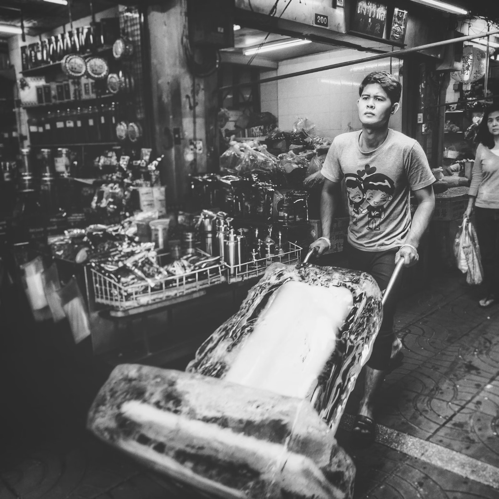 Homme transportant un grand bloc de glace dans un marché, illustrant les méthodes de conservation des aliments avant l'invention du réfrigérateur moderne.