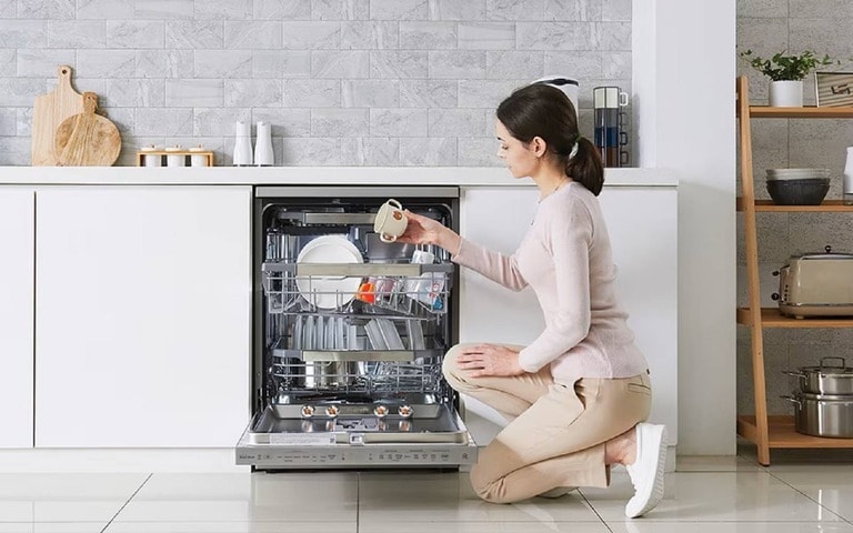 Une femme remplit un lave-vaisselle avec des ustensiles de cuisine, afin de mettre en valeur la facilité d’utilisation et l’efficacité de la technologie du lave-vaisselle.