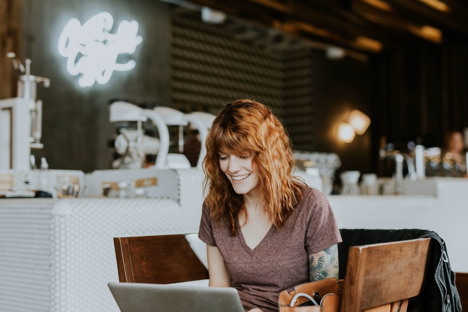 Femme souriante travaillant sur un ordinateur portable dans un café. 