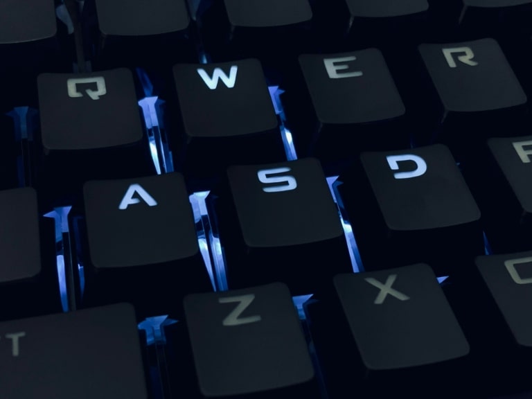  Un clavier rétroéclairé en gros plan avec une focalisation sur les touches Q, W, E, R, A, S, D, Z, et X illuminées en bleu.
