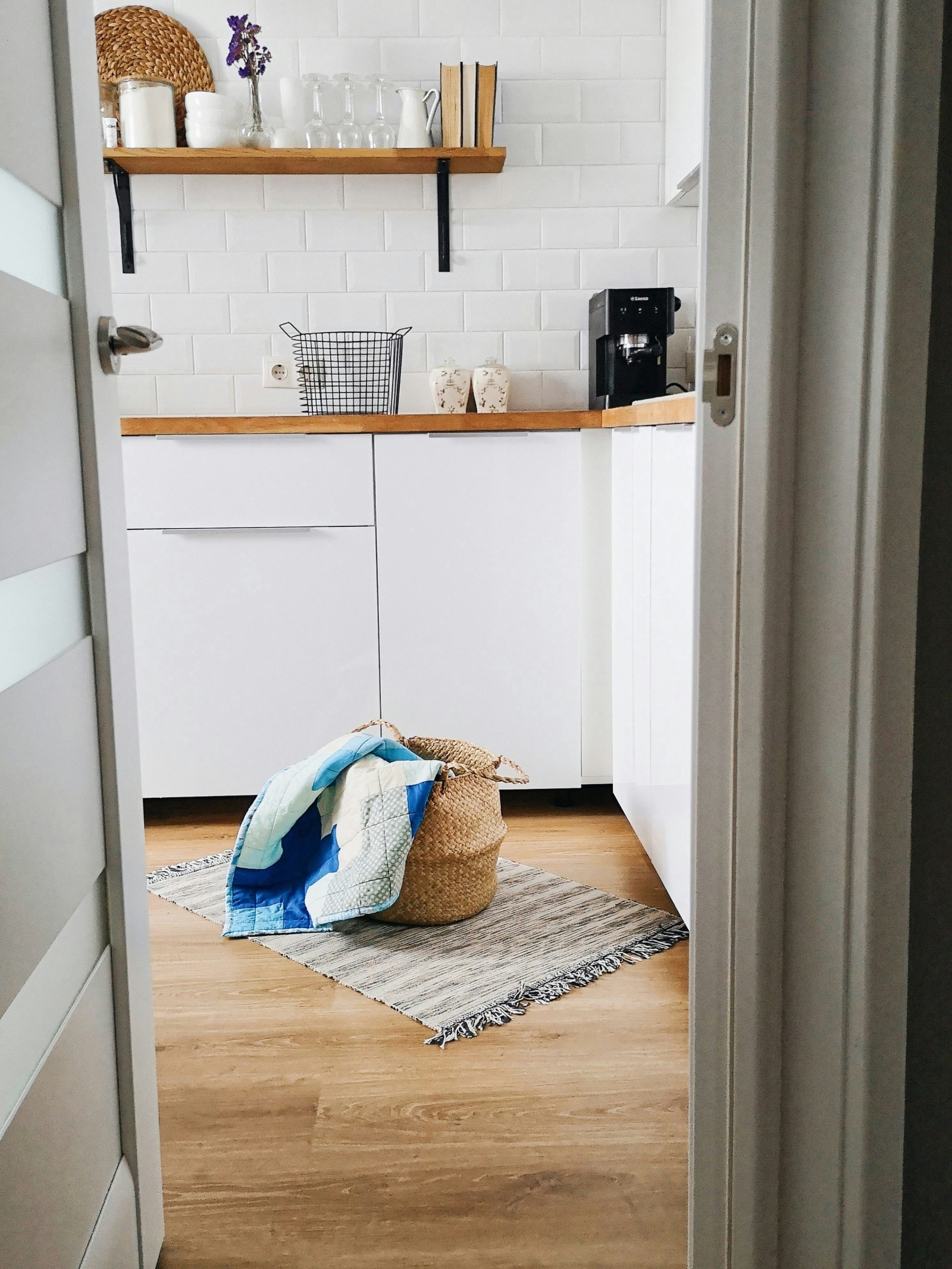 Un panier à linge posé sur un tapis texturé dans une cuisine moderne.
