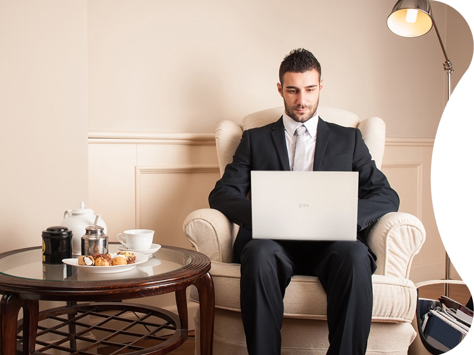 A male guest is working on a LG gram17 laptop in the hotel room. Thanks to its big screen, he can focus on whatever he is working at a diligent pace.