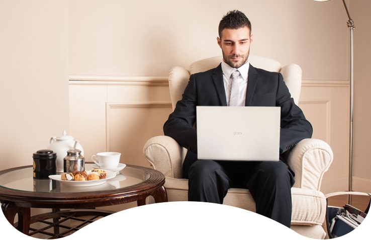 A male guest is working on a LG gram17 laptop in the hotel room. Thanks to its big screen, he can focus on whatever he is working at a diligent pace.