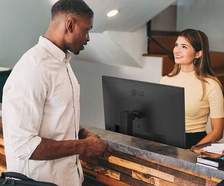 A female receptionist is talking to a man at the front desk.	