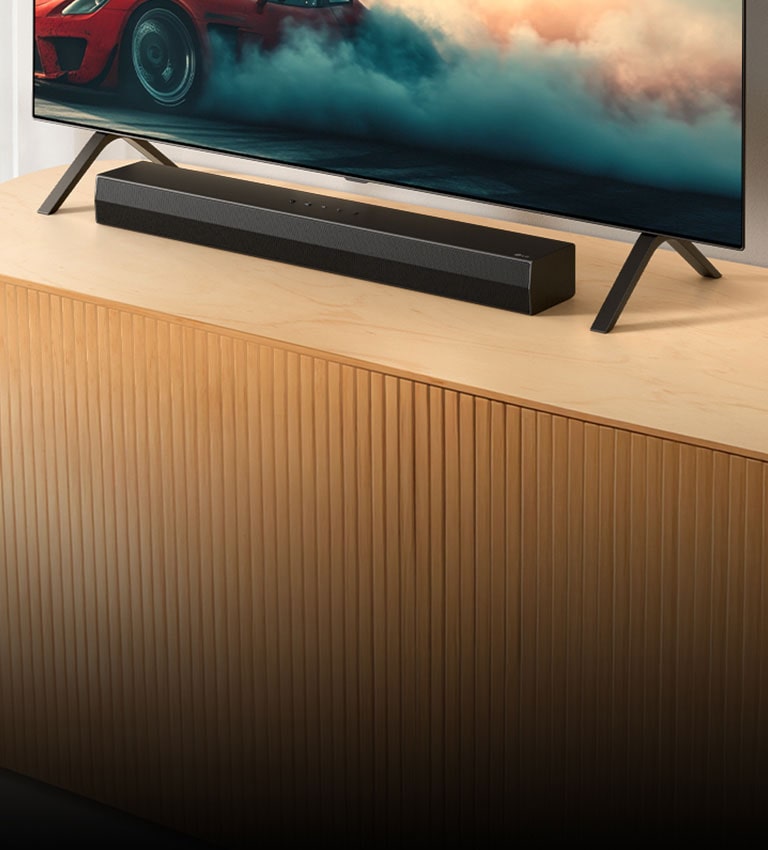 Το LG Soundbar S20A τοποθετε?ται σε μια ξ?λινη κονσ?λα τηλε?ραση?, κ?τω απ? μια τηλε?ραση και αν?μεσα στι? β?σει? τη? τηλε?ραση?. Στην τηλε?ραση εμφαν?ζεται ?να κ?κκινο αυτοκ?νητο με καπν?.