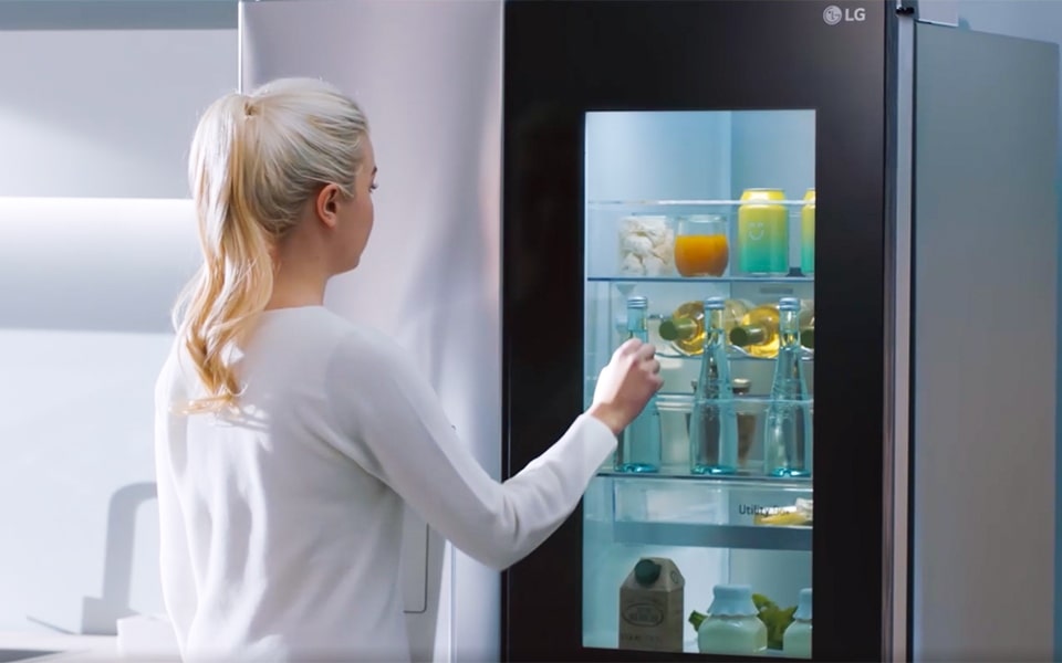 A woman with a blonde pony tails knocks twice on her LG InstaView? smart refrigerator