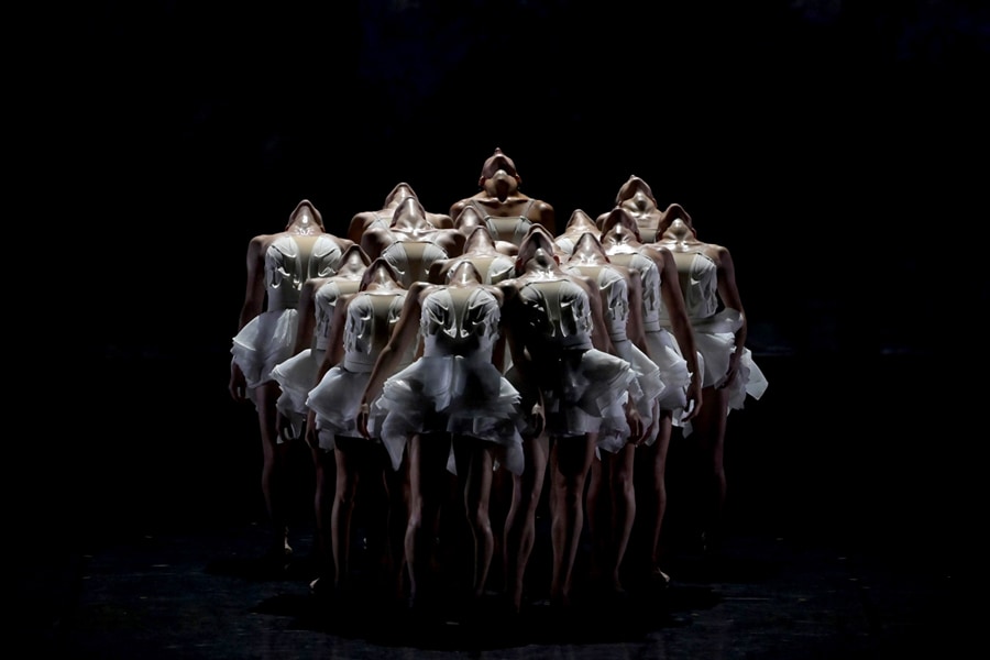 Una foto di ballerine sul palco con le teste inclinate all’indietro.