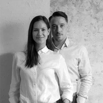 Un uomo e una donna in piedi davanti a un muro grigio.