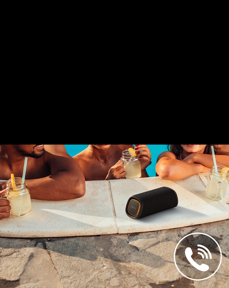 LG XBOOM Go XG7 ir novietots pie baseina. Trīs cilvēki runā pa ska?runi baseinā.