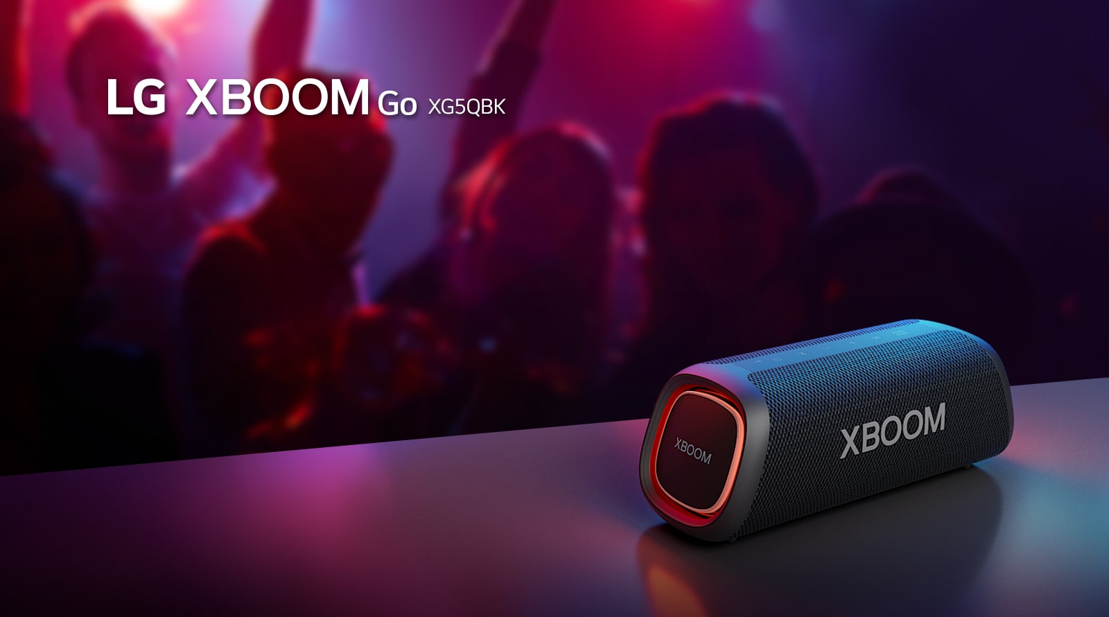 LG XBOOM Go XG5 ir novietots uz metāla galda ar ieslēgtu oran?o apgaismojumu. Pie galda cilvēki bauda mūziku.