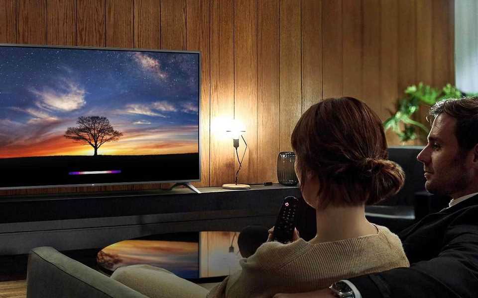 Pāris skatās LG televizoru savā mājas kinozālē.