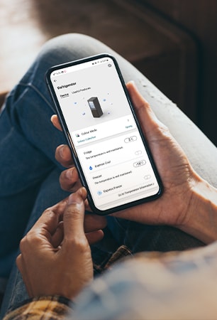 Bilde som viser en app som lar deg manipulere kj?leskapet til ? holde telefonen i h?nden.
