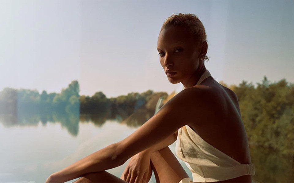 A woman sitting by the river wearing natural clothes.
