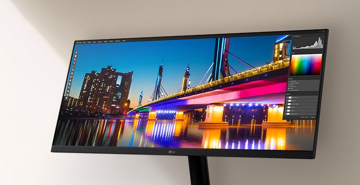 Monitor LG ultra-larg care afi?eaz? un peisaj urban nocturn intens, cu un pod luminat puternic ?i o reflexie, prezentat ?n cadrul unei interfe?e software de editare foto care eviden?iaz? instrumentele de culoare ?i contrast.	