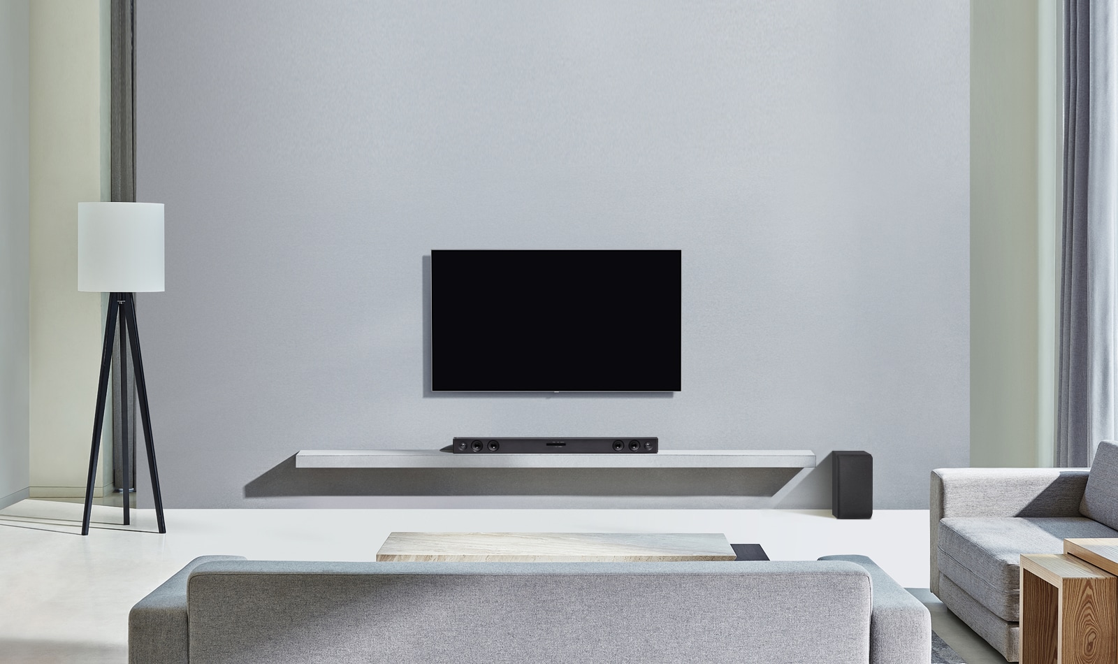Televizorul LG este ag??at pe peretele gri. Iar bara LG SQC2 este a?ezat? pe raftul din camera de zi. Iar subwoofer-ul este a?ezat lang? raft. Imaginea ilustreaz? faptul c? bara de sunet se asorteaz? cu televizorul LG ?i completeaz? interiorul.