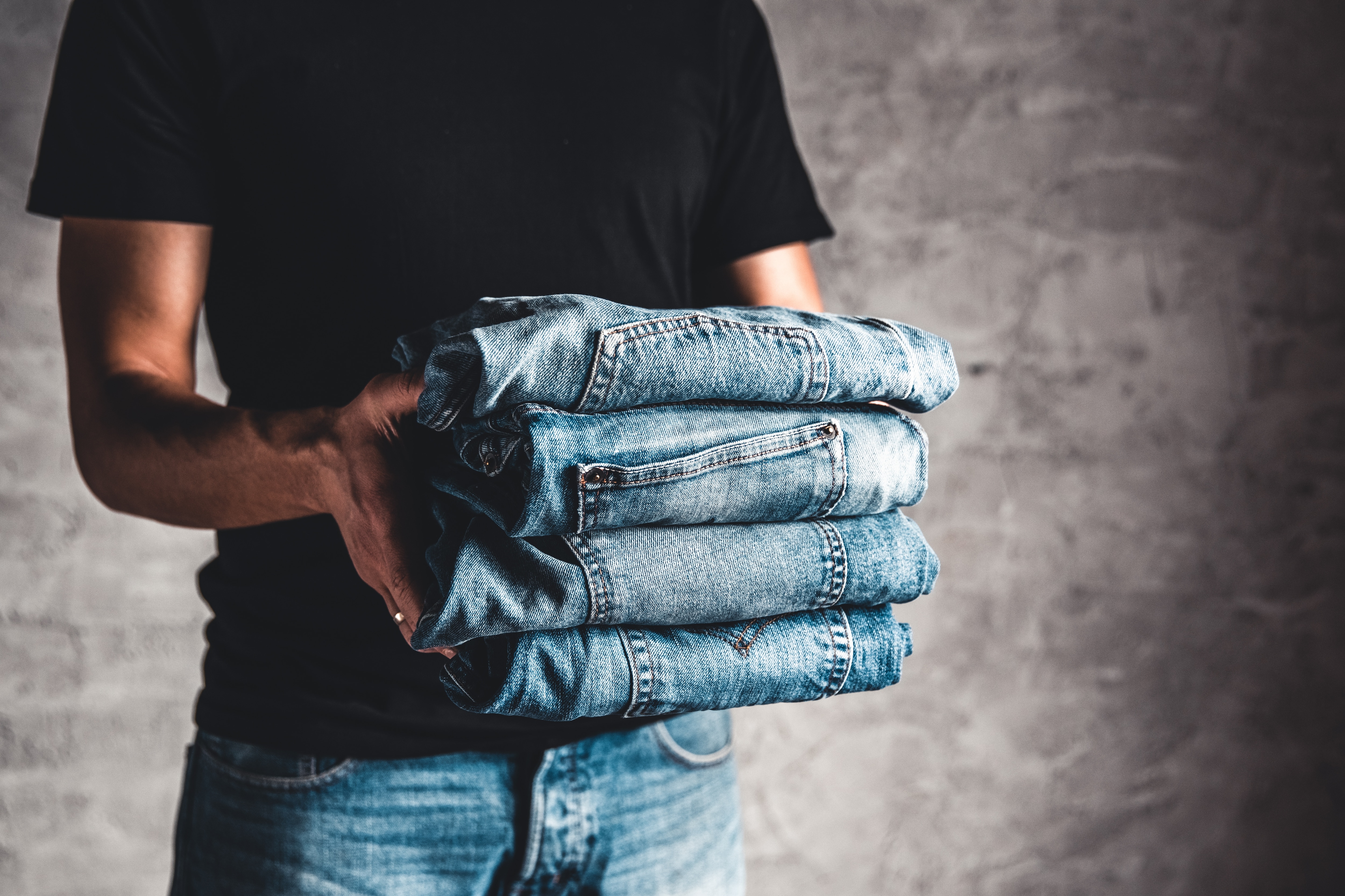 close-up-stack-of-folded-denim-blue-jeans-in-hand-2021-12-09-06-30-03-utc.JPG