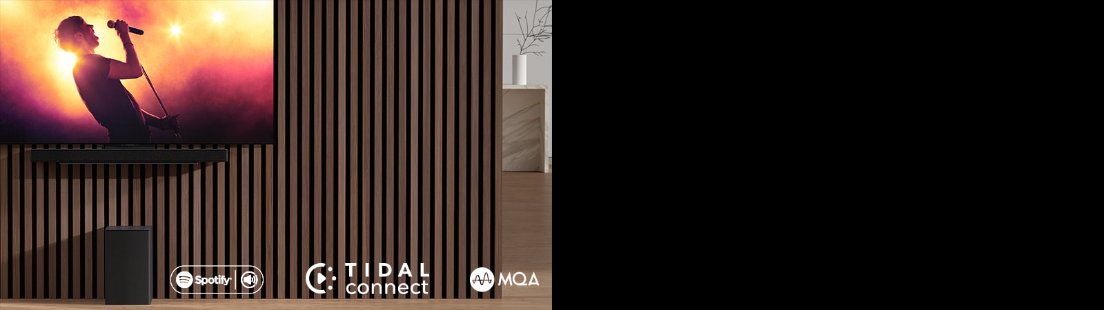 LG OLED C se nalazi na zidu, ispod je postavljen LG Sound Bar SC9S na ekskluzivnom nosa?u. Niskotonac se nalazi ispod toga. Na televizoru se prikazuje scena sa koncerta.