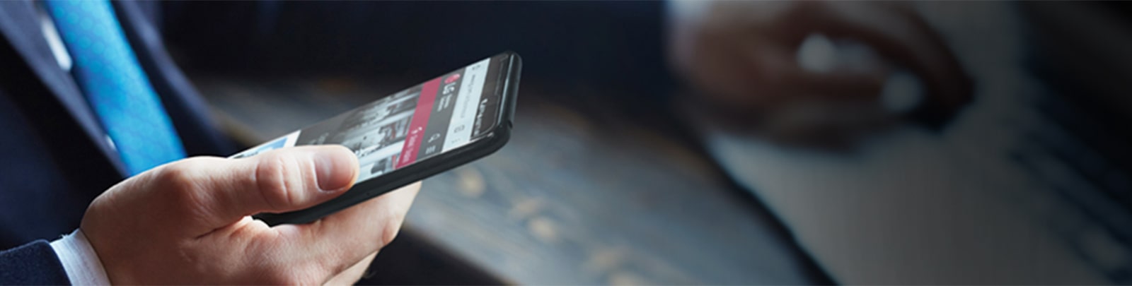 An image of a man holding a smartphone with LG web page on the screen.
